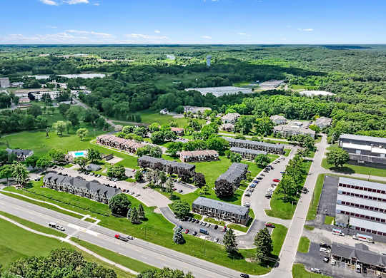 A bird's eye view of a large green campus with buildings and roads.