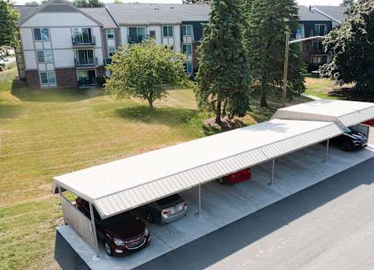 A carport with two cars parked in front of a house.