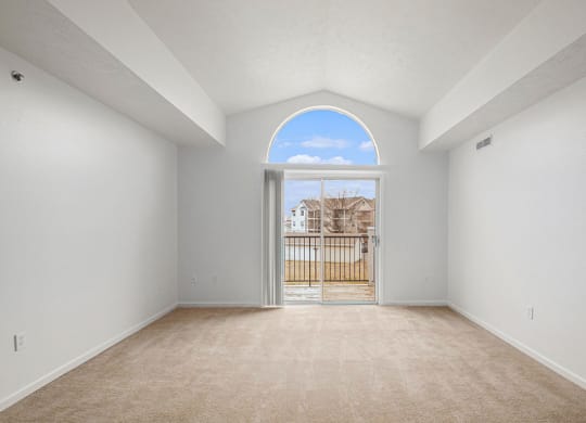 living room with a cathedral ceiling and a door to a balcony  at Black Sand Apartment Homes, Lincoln, 68504