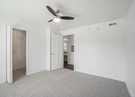 A bedroom with a ceiling fan, walk-in closet, and carpeted floor at Byron Lakes Apartments, Byron Center, Michigan