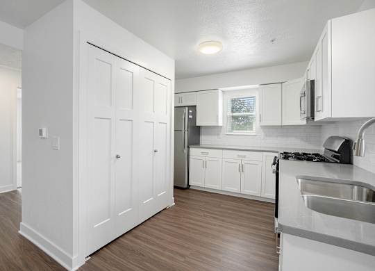 A kitchen with a window, white cabinets and a hard-surface floor at Byron Lakes Apartments, Byron Center, Michigan
