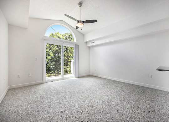 A living room with a ceiling fan and carpeted floor at Byron Lakes Apartments, Byron Center, MI