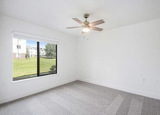 A bedroom with a ceiling fan at Byron Lakes Apartments in Byron Center, MI