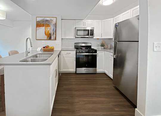 a kitchen with stainless steel appliances and white cabinets at Byron Lakes Apartments in Byron Center, MI