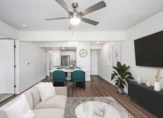 A living room with a white couch and a ceiling fan at Byron Lakes Apartments in Byron Center, MI