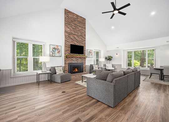 A community building with a fireplace and a grey couch at Byron Lakes Apartments, Byron Center, MI