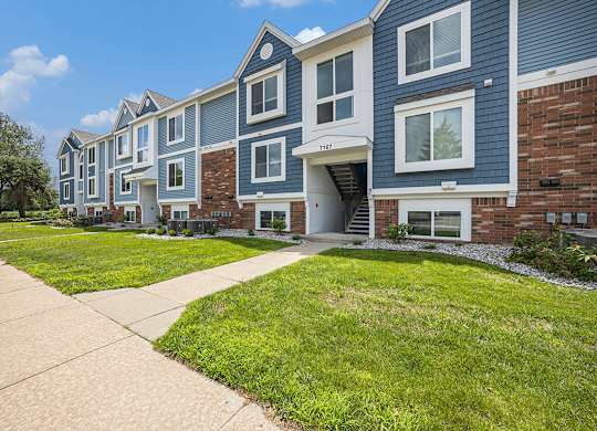 An apartment building with a sidewalk in front at Byron Lakes Apartments, Byron Center, MI