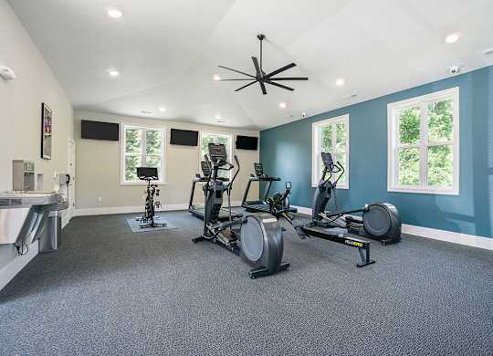 A fitness center with exercise bikes and a television above them at Byron Lakes Apartments in Byron Center, MI