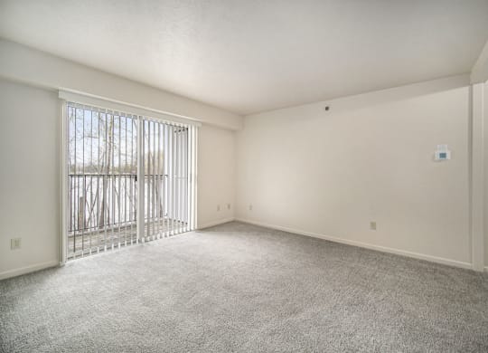 an empty living room with a sliding glass door to a balcony at Canal 2 Apartments in Lansing, MI