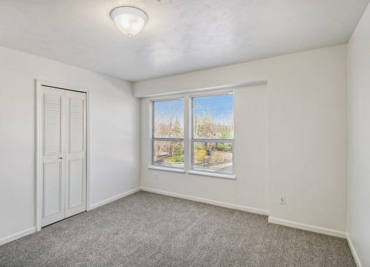 Bedroom with a large window and a walk in closet at Canal 2 Apartments, Lansing, Michigan