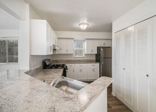 an end style kitchen with white cabinets and a window at Canal 2 Apartments, Lansing, Michigan