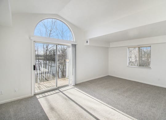 Enlarged living room with a cathedral ceiling and door to a balcony at Canal 2 Apartments, Lansing, Michigan