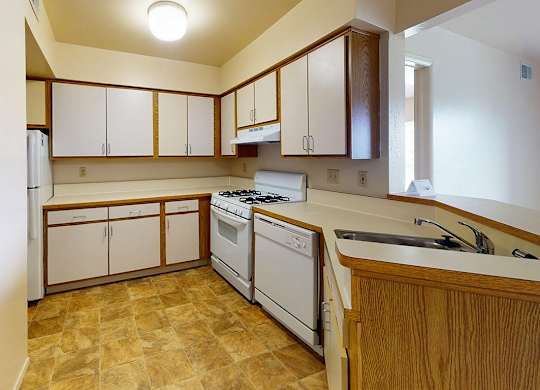 A kitchen with white appliances and wooden cabinets at Canal Club Apartments, Lansing, 48917