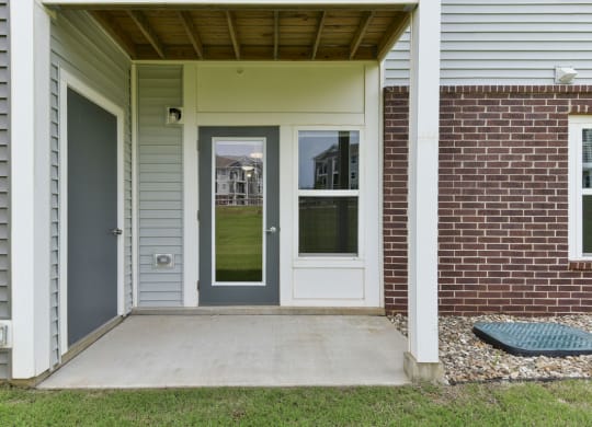 a front porch with a gray door and a red brick wallat Chase Creek Apartment Homes, Alabama