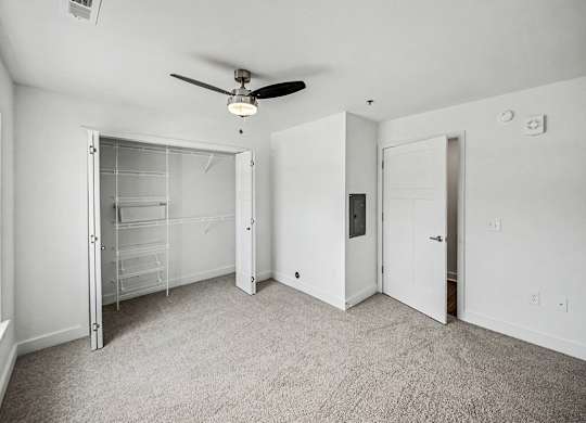 A room with a ceiling fan and carpeted floor.