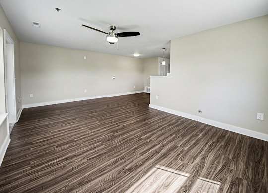 A room with a ceiling fan and wooden flooring.