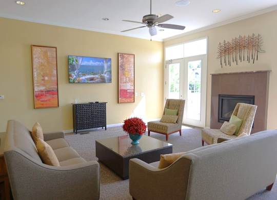 A living room with a fireplace, chairs, and a painting.