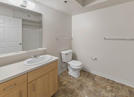 A bathroom with a toilet, sink, and mirror at Colonial Pointe at Fairview Apartments, Bellevue, 68123