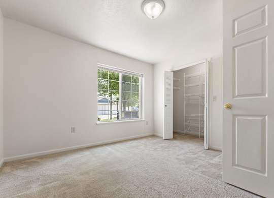 A bedroom with a large window and walk-in closet at Colonial Pointe at Fairview Apartments, Bellevue, 68123