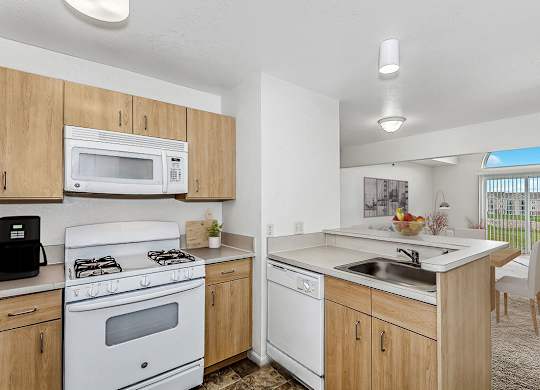 A kitchen with white appliances and wooden cabinets at Colonial Pointe at Fairview Apartments, Bellevue, Nebraska
