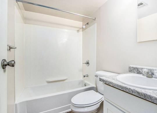 A white bathroom with a toilet, sink, and bathtub at Concord Place Apartments, Kalamazoo, MI