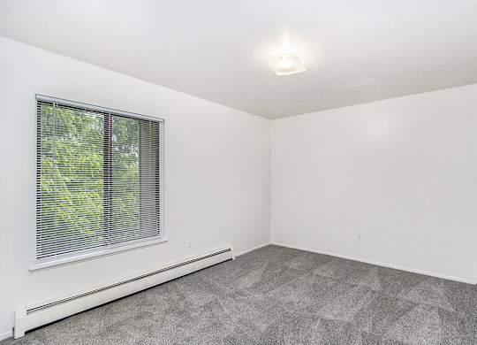 A bedroom with a window and carpeted floor at Concord Place Apartments, Kalamazoo, MI