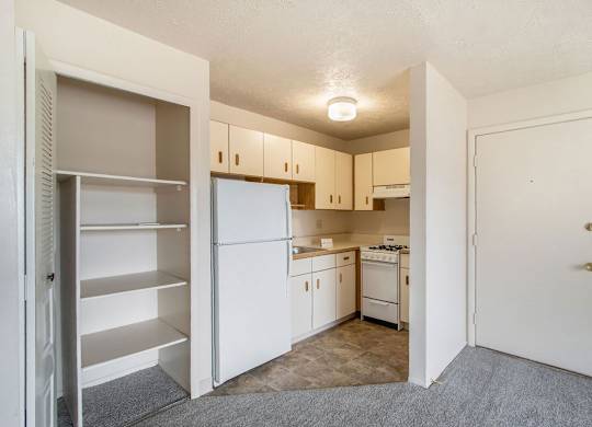 A kitchen with white appliances and a closet with shelves at Concord Place Apartments, Kalamazoo, MI, 49009