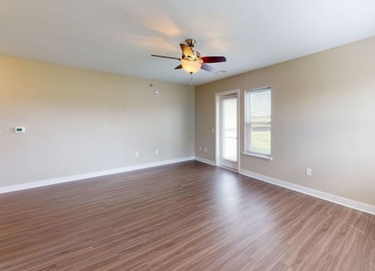 Enlarged living room with hard surface flooring and a ceiling fan at Copper Creek Apartment Homes in Maize, KS