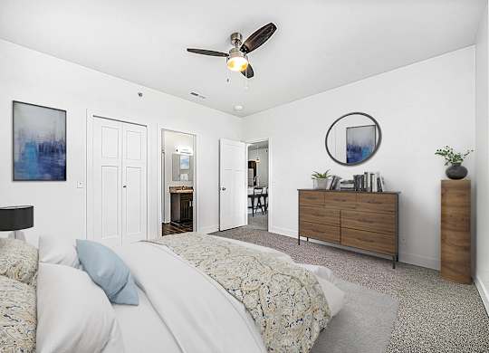 A bedroom with a bed, dresser, ceiling fan and ensuite at Copper Creek Apartment Homes, Maize, Kansas