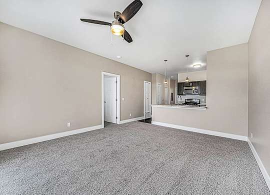 A living room with a ceiling fan and carpeted floor an empty bedroom with a ceiling fan and ensuite at Copper Creek Apartment Homes, Kansas, 67101