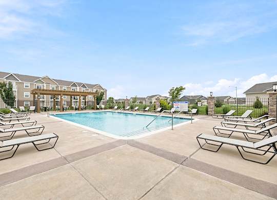 Outdoor swimming pool with lounge chairs and pergola at Copper Creek Homes Apartments, Kansas