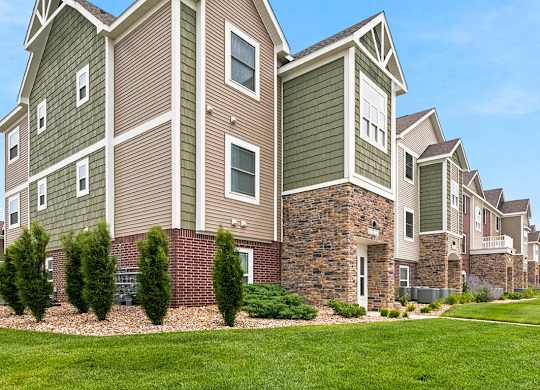 Residential building exterior with stone and siding accents at Copper Creek Homes Apartments, Maize