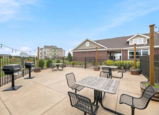 Outdoor grilling patio with seating areas and string lights at Copper Creek Homes Apartments, Maize, Kansas