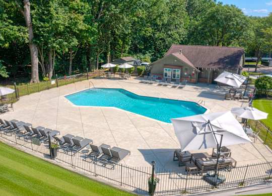 A large outdoor swimming pool surrounded by lawn chairs and umbrellas