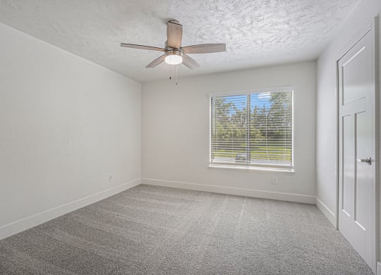 bedroom with a ceiling fan and a large window at The Crossings Apartments, Michigan, 49508