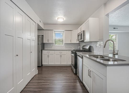 a kitchen with white cabinets and a window at The Crossings Apartments, Michigan, 49508