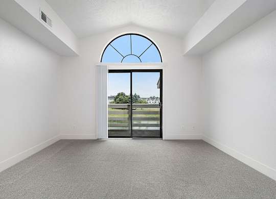 A living room with a cathedral ceiling and large arched window and a view at The Crossings Apartments, Grand Rapids, MI, 49508