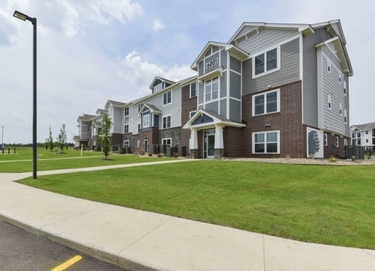 the outlook of a row of apartment buildings with green grass and sidewalks at Dodson Pointe Apartment Homes, Rogers, AR, 72758