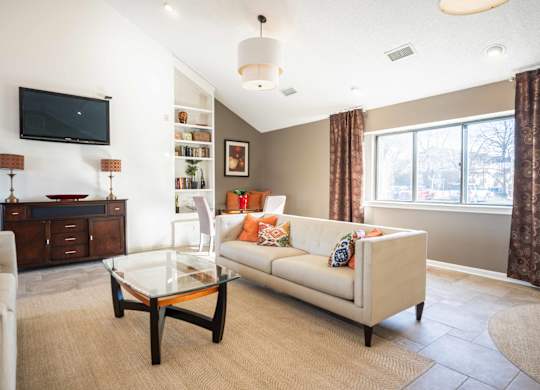 A living room with a white couch and a glass coffee table.