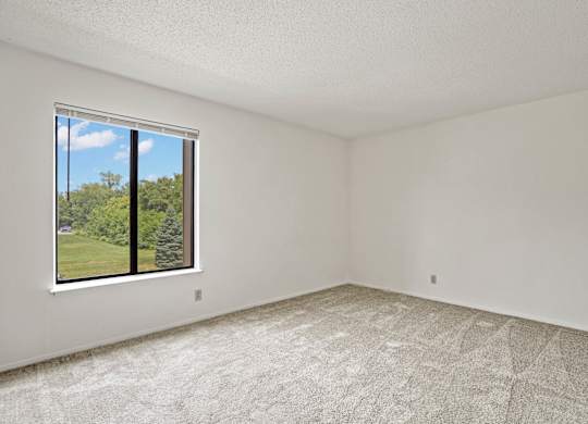 A room with a large window and carpeted floor at Beacon Hill and Great Oaks Apartments, Rockford, Illinois