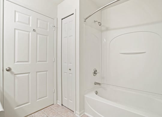 A white bathroom with a tub and a door at Towne Lakes Apartments, Grand Chute