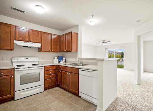 A kitchen with white appliances and brown cabinets at Towne Lakes Apartments, Grand Chute