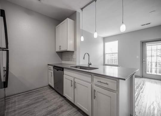 an empty kitchen with white cabinets and a black counter top at Bella Vista Apartments, Fishers, IN