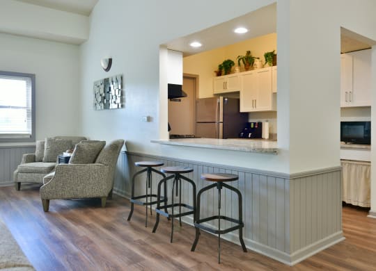 a kitchen and living room with a bar and stools at Heatherwood Apartments, Grand Blanc