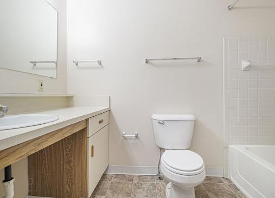 A white toilet sits in a bathroom next to a sink and a bathtub at Dupont Lakes Apartments, Fort Wayne