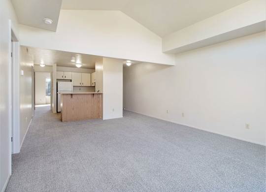 A spacious living and dining room with a kitchen in the background at Dupont Lakes Apartments, Fort Wayne