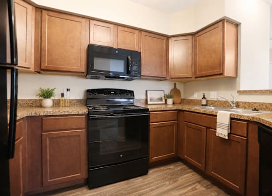 A kitchen with wooden cabinets and black appliances.