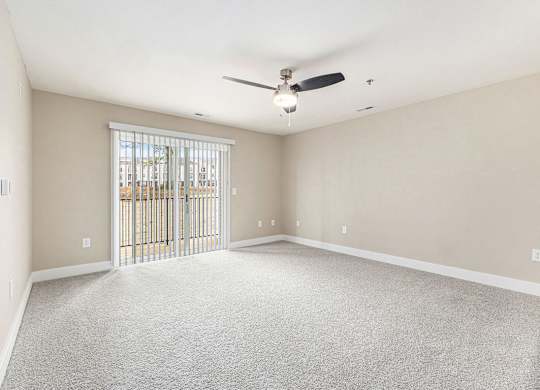 A carpeted living room with a ceiling fan and a sliding glass door Spacious bedroom with large windows and walk in closet at Eagle Ridge Apartment Homes,  Michigan 49685