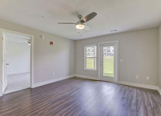 A living room with a ceiling fan and hard surface flooring Spacious bedroom with large windows and walk in closet at Eagle Ridge Apartment Homes,  Michigan 49685