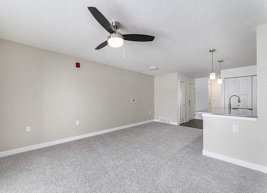 A living room with a ceiling fan and a carpeted floor at Eagle Ridge Apartment Homes, Traverse City, Michigan